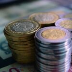Close-up of stacked gold and silver coins on various currency notes, symbolizing wealth and savings.
